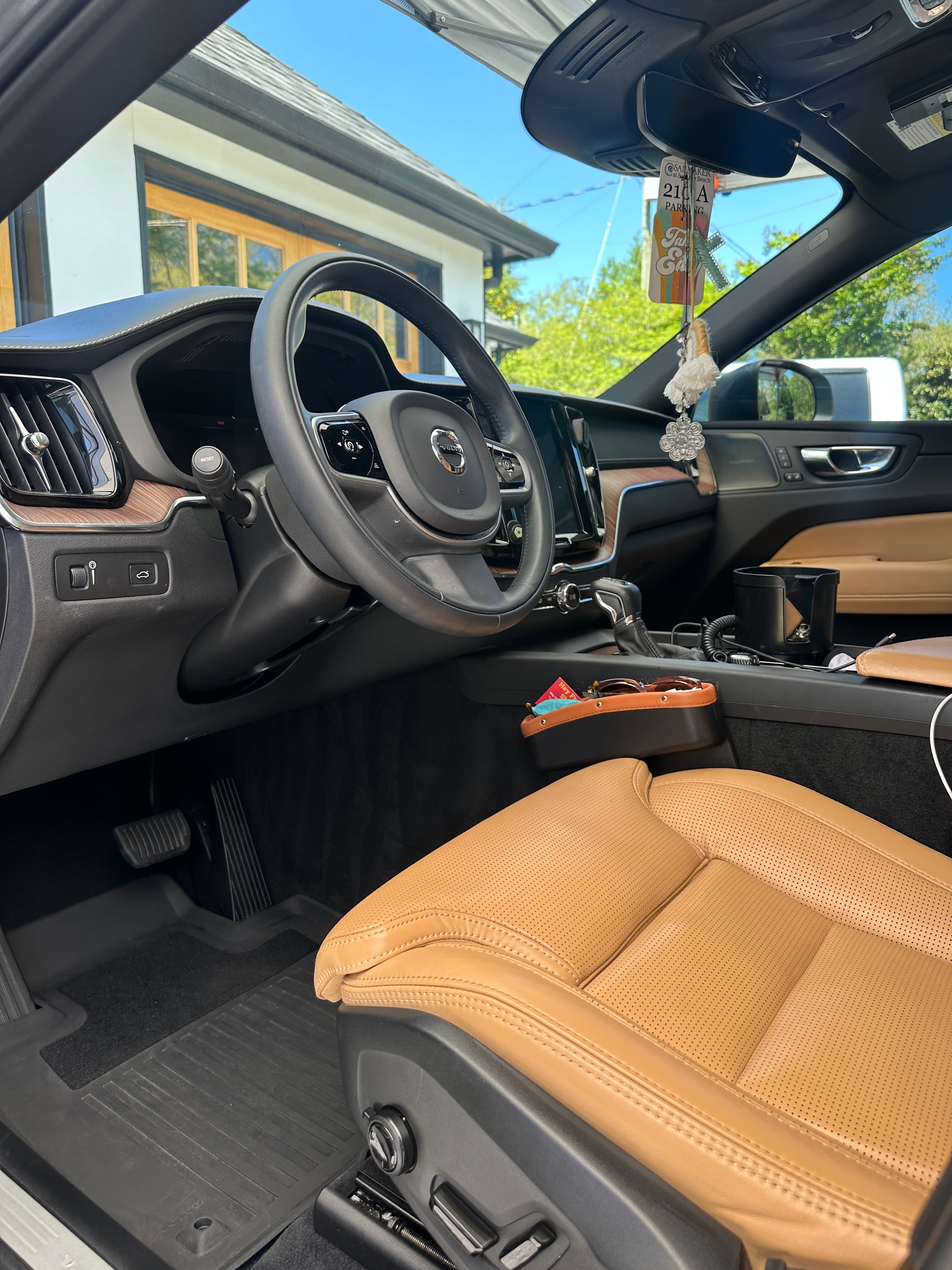 Modern Volvo interior with tan perforated leather seats, black steering wheel, and wood grain dashboard.