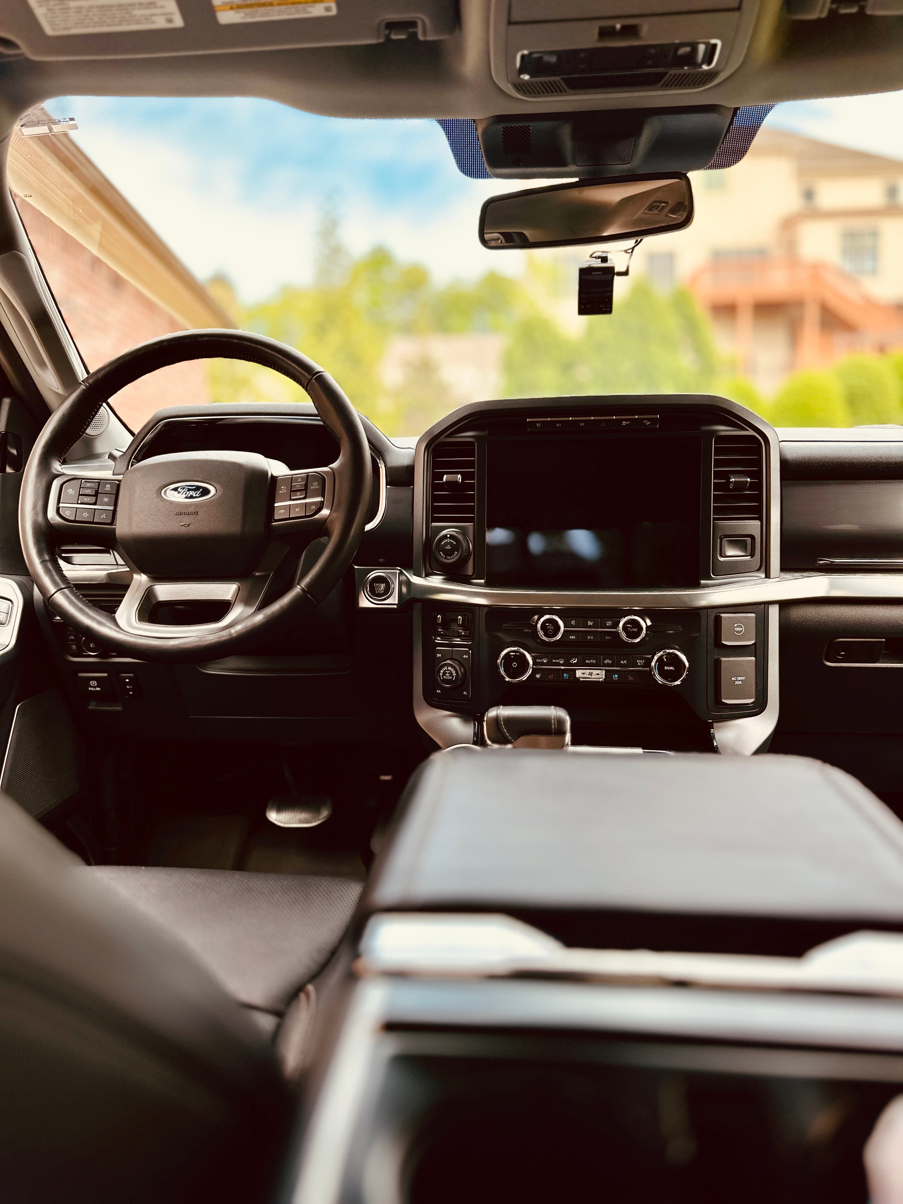 Modern Ford truck interior with a leather steering wheel, large touchscreen, and center console.